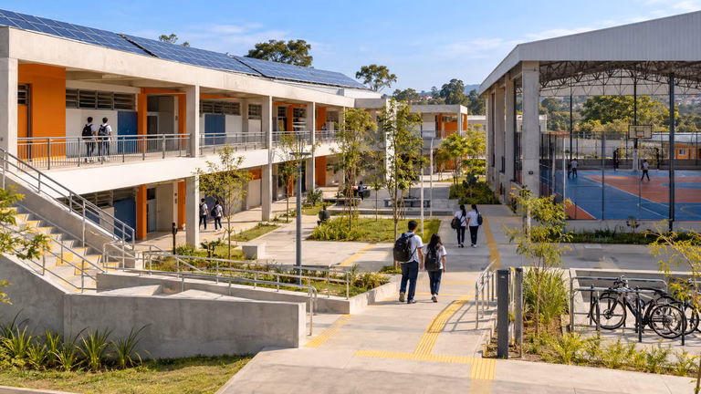 Nova escola estadual de São Paulo construída pela PPP Novas Escolas com fachada, pátio e quadra esportiva